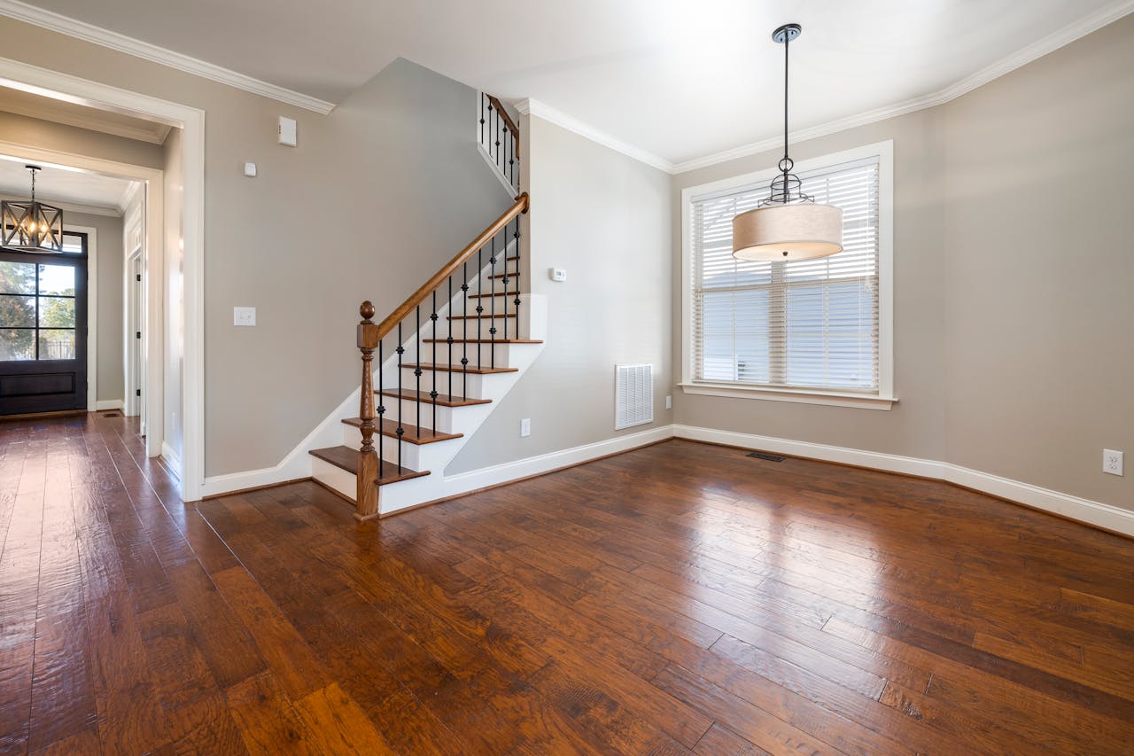 Bright and airy room with wooden floors and staircase, ideal for modern living.
