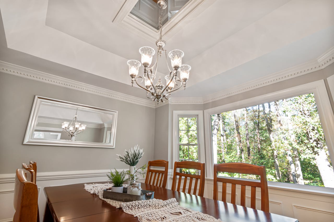 Beautiful dining room featuring a classic chandelier, wooden furniture, and ample natural light from large windows.